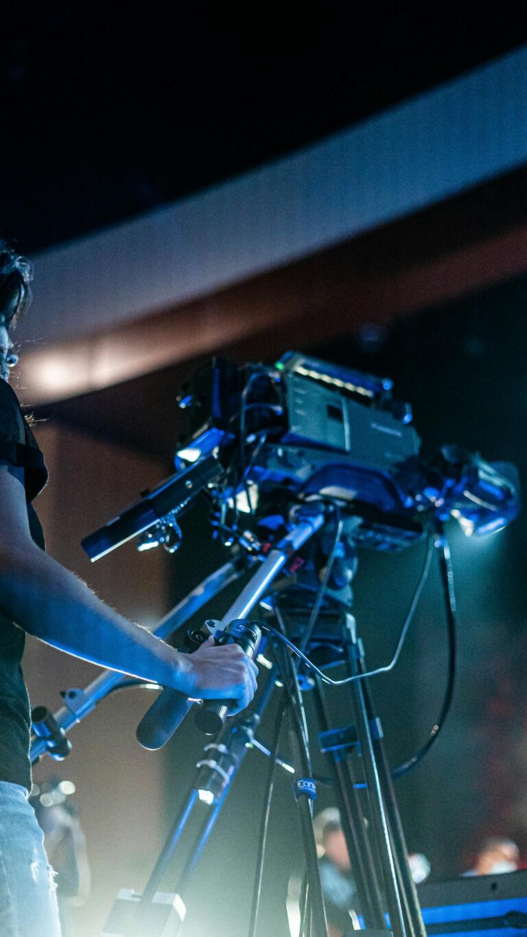 Crop person using professional camera to shoot video of music show during performance